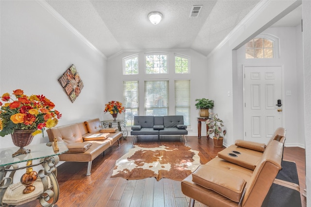 living area featuring vaulted ceiling, hardwood / wood-style floors, a textured ceiling, and ornamental molding