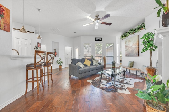 living room featuring visible vents, dark wood finished floors, a textured ceiling, and baseboards