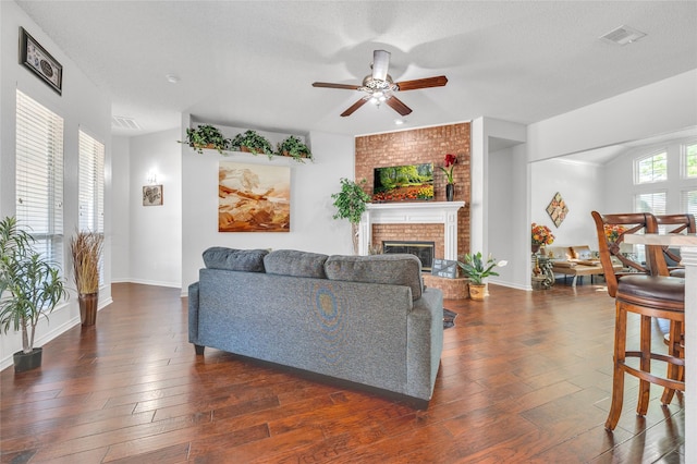 living room featuring ceiling fan, dark wood-type flooring, a fireplace, and baseboards