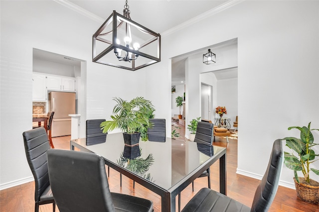 dining space with baseboards, ornamental molding, and wood finished floors