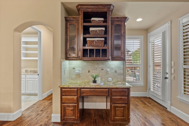 home office with baseboards, arched walkways, and wood finished floors