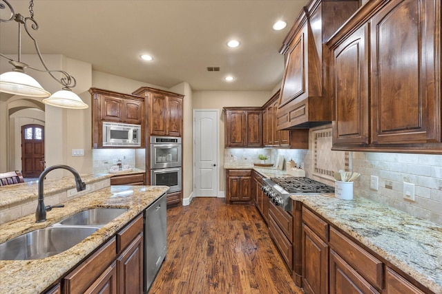 kitchen featuring appliances with stainless steel finishes, a sink, decorative light fixtures, dark wood-type flooring, and visible vents
