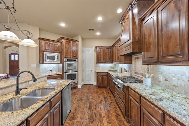 kitchen featuring visible vents, dark wood finished floors, stainless steel appliances, pendant lighting, and a sink