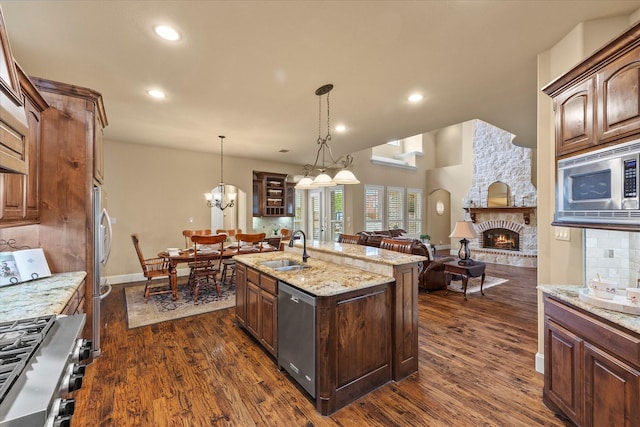 kitchen featuring dark wood finished floors, a fireplace, stainless steel appliances, open floor plan, and a sink