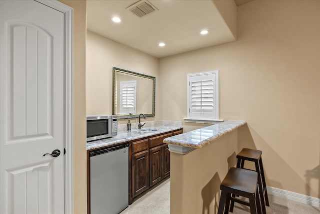 interior space with a sink, recessed lighting, stainless steel microwave, refrigerator, and visible vents