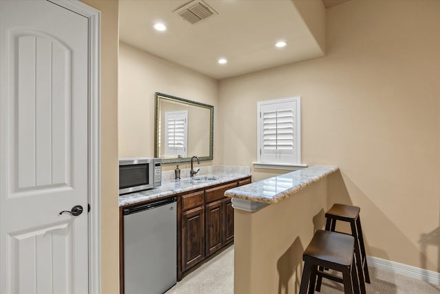 bar with visible vents, light colored carpet, stainless steel microwave, fridge, and a sink