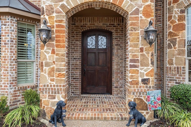 view of exterior entry with a standing seam roof and brick siding