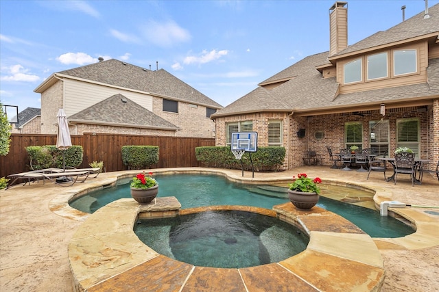 view of pool featuring a pool with connected hot tub, fence, and a patio