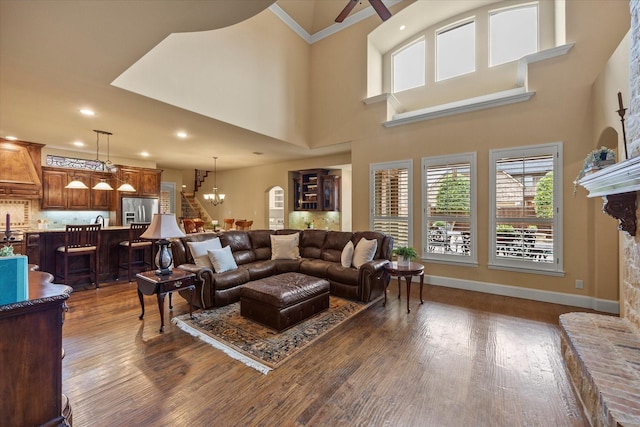living area featuring ceiling fan, a fireplace with raised hearth, ornamental molding, baseboards, and dark wood-style floors