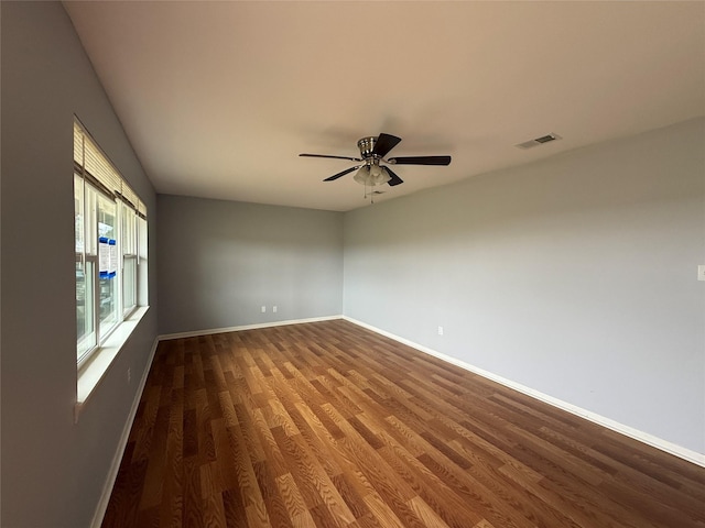 empty room with visible vents, ceiling fan, baseboards, and wood finished floors