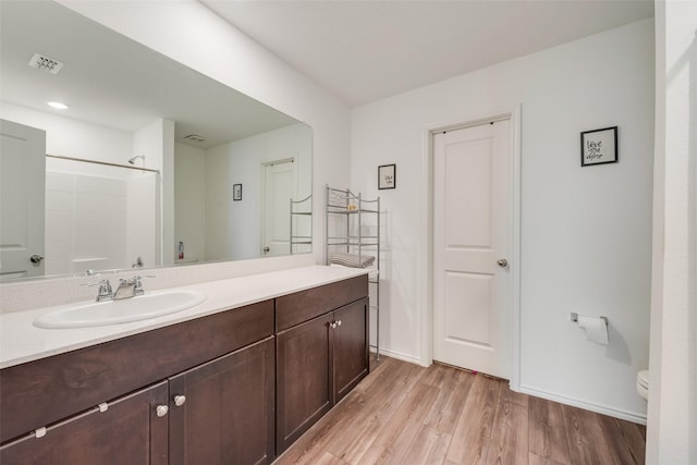 full bathroom featuring visible vents, toilet, wood finished floors, walk in shower, and vanity