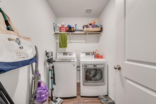 washroom featuring laundry area, separate washer and dryer, light wood-type flooring, and visible vents