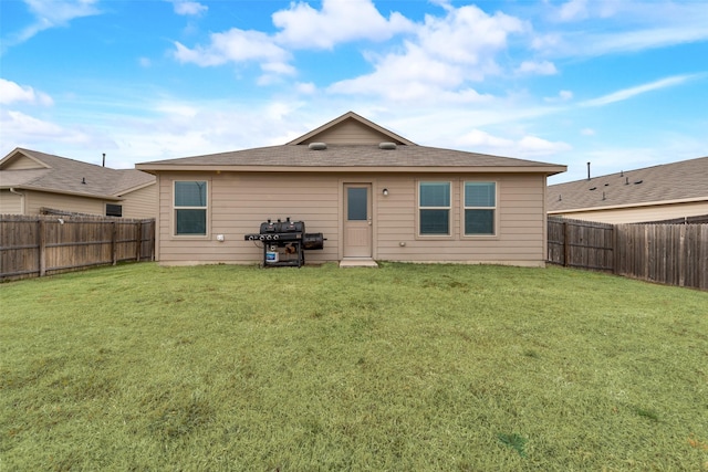 rear view of house featuring a yard and a fenced backyard