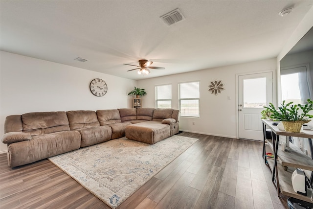 living area with wood finished floors, visible vents, and a ceiling fan