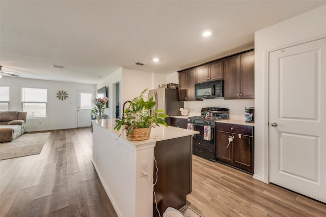 kitchen featuring black appliances, light wood finished floors, and dark brown cabinetry