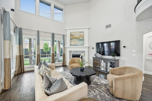 living room with a fireplace, visible vents, a high ceiling, wood finished floors, and baseboards