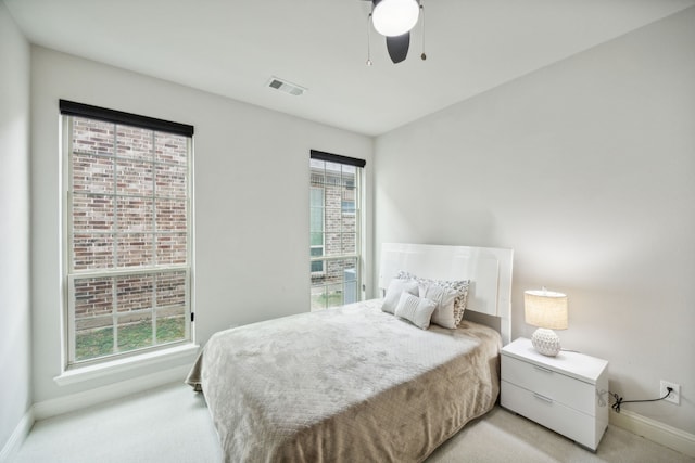 bedroom featuring visible vents, light carpet, baseboards, and multiple windows