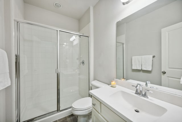 bathroom featuring toilet, a stall shower, and vanity