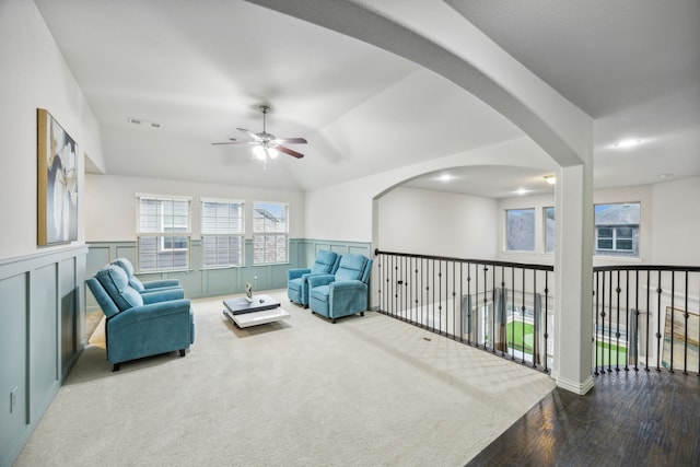 sitting room featuring lofted ceiling, a wainscoted wall, carpet flooring, visible vents, and a ceiling fan