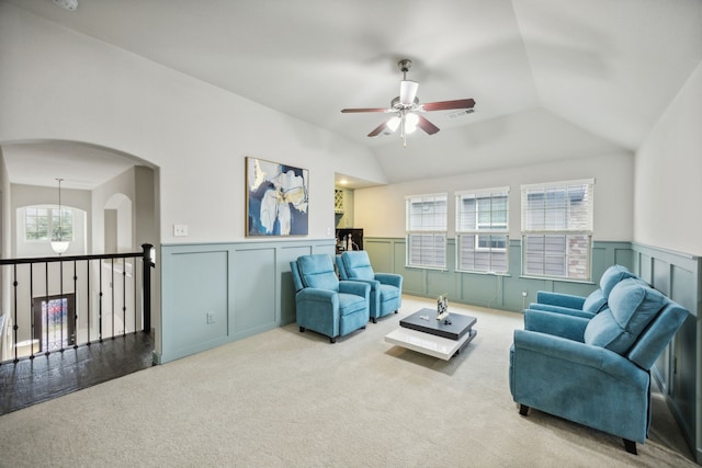 carpeted living room featuring lofted ceiling, a decorative wall, wainscoting, and a healthy amount of sunlight