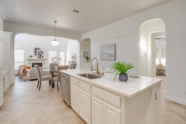 kitchen featuring light tile patterned floors, visible vents, a sink, a fireplace, and stainless steel dishwasher