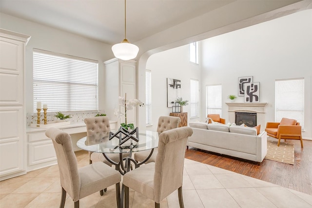 dining space with arched walkways, a glass covered fireplace, and light tile patterned floors