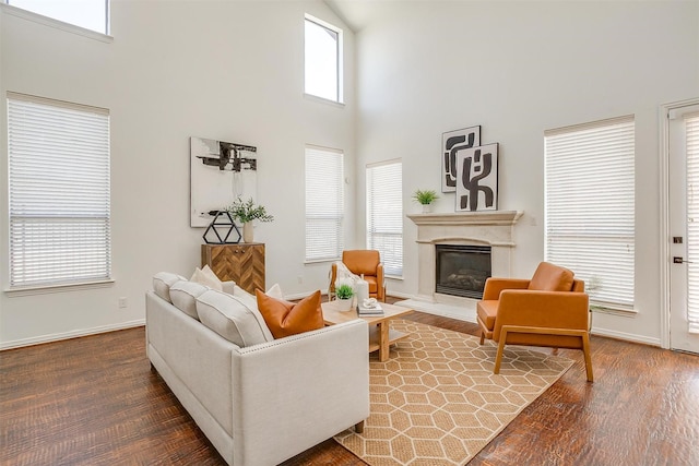 living room with a glass covered fireplace, wood finished floors, and baseboards