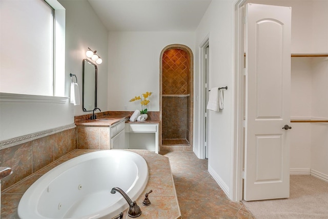 bathroom featuring a tub with jets, a shower stall, vanity, and baseboards