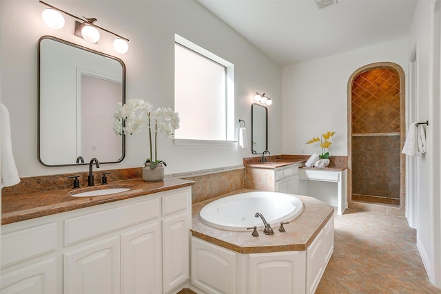 full bathroom with two vanities, a sink, a tile shower, and a bath