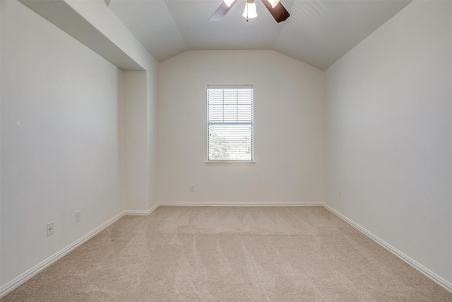 empty room featuring light colored carpet, vaulted ceiling, baseboards, and ceiling fan