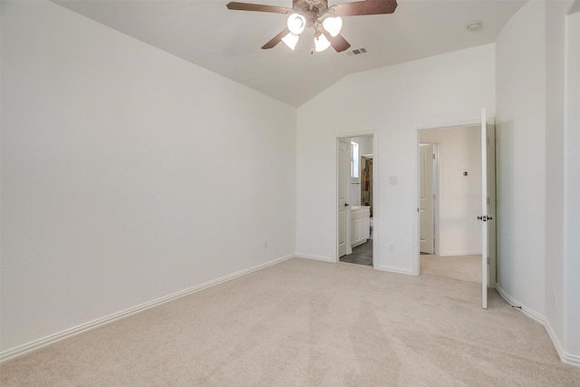 unfurnished bedroom with light carpet, baseboards, visible vents, ensuite bathroom, and vaulted ceiling