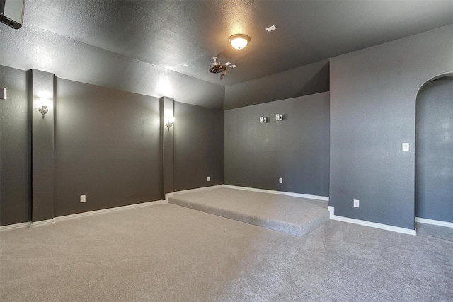 carpeted spare room featuring lofted ceiling, arched walkways, and baseboards