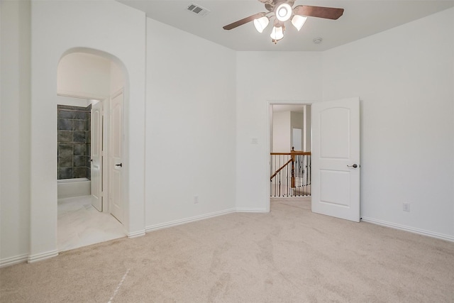 unfurnished room with arched walkways, ceiling fan, carpet, and visible vents