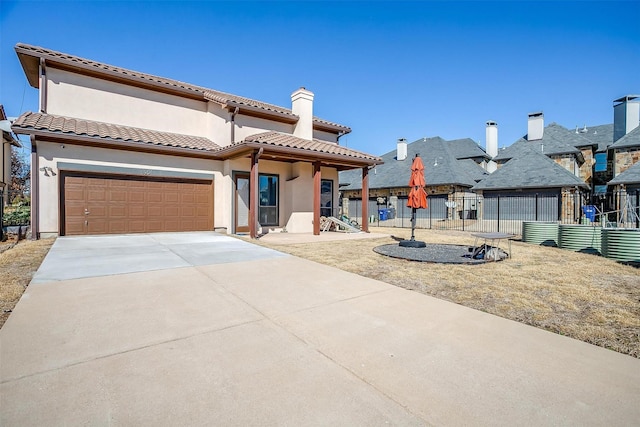 view of front of home featuring concrete driveway, a tile roof, fence, and stucco siding