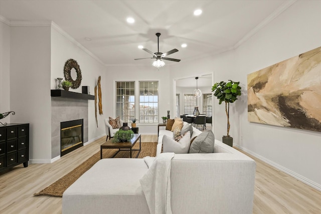 living room with ornamental molding, baseboards, light wood finished floors, and a tiled fireplace