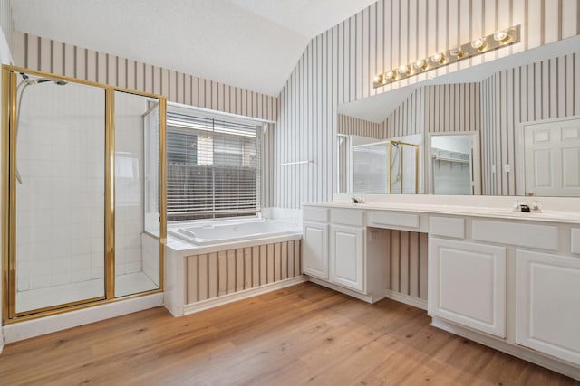 full bath with lofted ceiling, a textured ceiling, a garden tub, a stall shower, and wallpapered walls