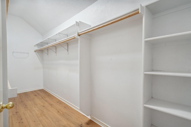 walk in closet featuring light wood-style floors and vaulted ceiling