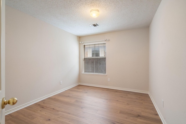 empty room featuring baseboards, a textured ceiling, visible vents, and wood finished floors