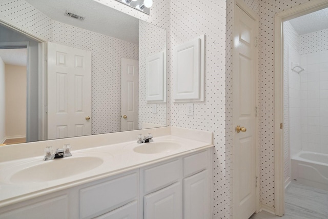 full bathroom featuring wallpapered walls, visible vents, and a sink