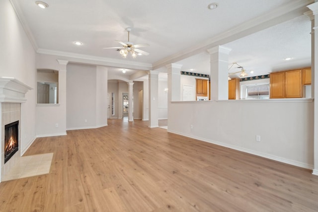 unfurnished living room with a fireplace, decorative columns, ceiling fan, light wood-type flooring, and baseboards