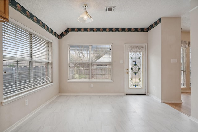 spare room with a textured ceiling, visible vents, and baseboards