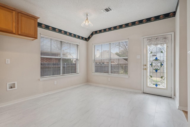 unfurnished dining area featuring lofted ceiling, visible vents, a textured ceiling, and baseboards