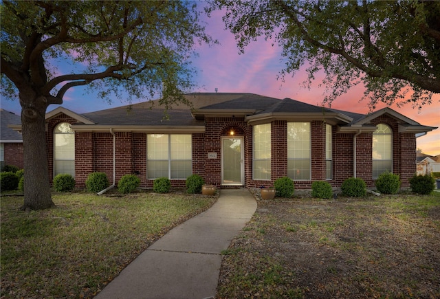 single story home featuring a yard and brick siding