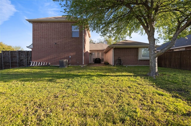 rear view of property featuring a yard, a fenced backyard, and brick siding