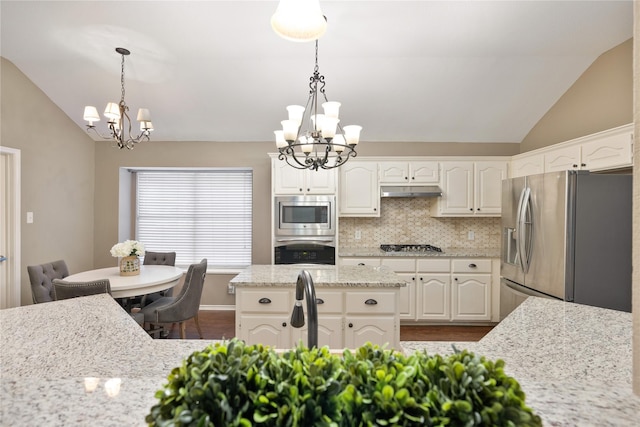 kitchen featuring lofted ceiling, under cabinet range hood, a chandelier, and stainless steel appliances