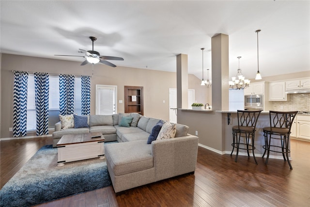 living area with vaulted ceiling, baseboards, dark wood finished floors, and ceiling fan with notable chandelier