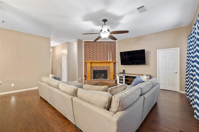 living room featuring dark wood-style flooring, a fireplace, visible vents, and baseboards