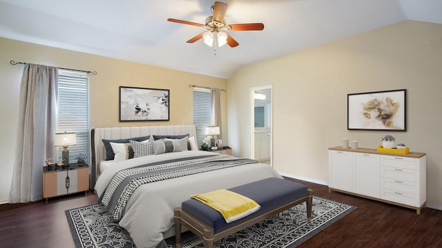 bedroom featuring dark wood-style flooring, vaulted ceiling, ensuite bath, and ceiling fan