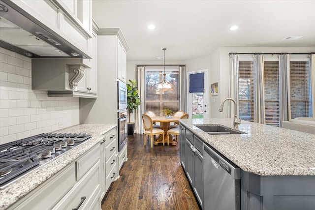 kitchen with dark wood finished floors, appliances with stainless steel finishes, white cabinetry, a sink, and under cabinet range hood