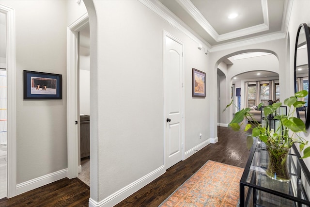 hallway with arched walkways, ornamental molding, wood finished floors, and baseboards